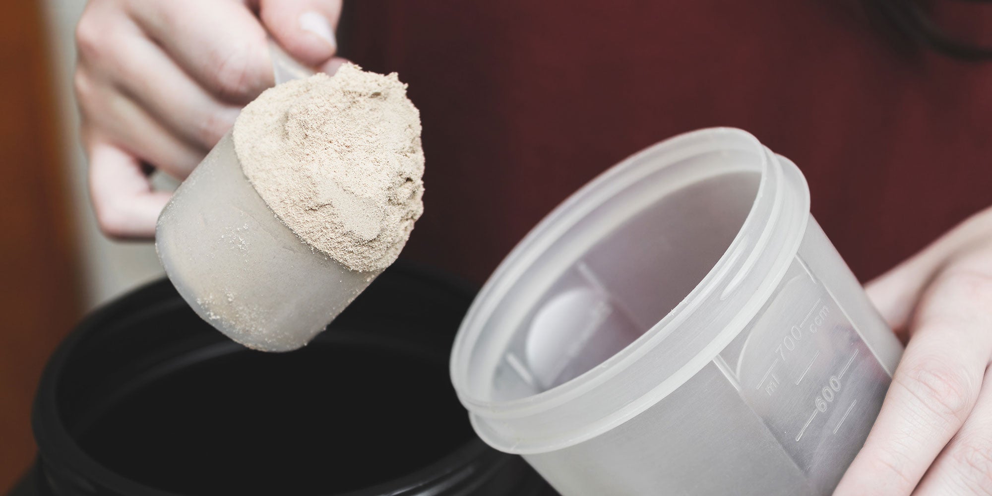 Protein powder being poured into protein shaker bottle